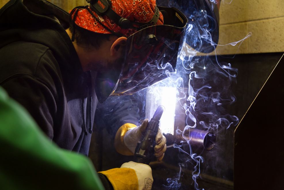 Welding students assisting each other.