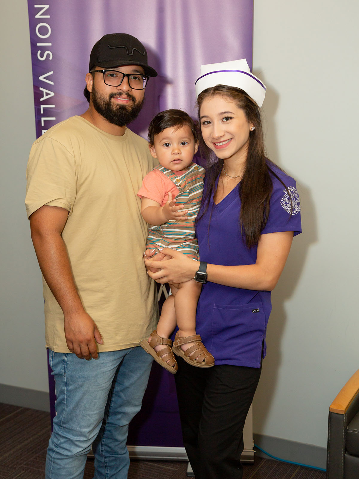 Adult student at graduation with her child and spouse