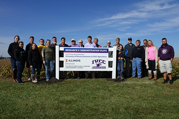 group of people by research and demonstration plot sign